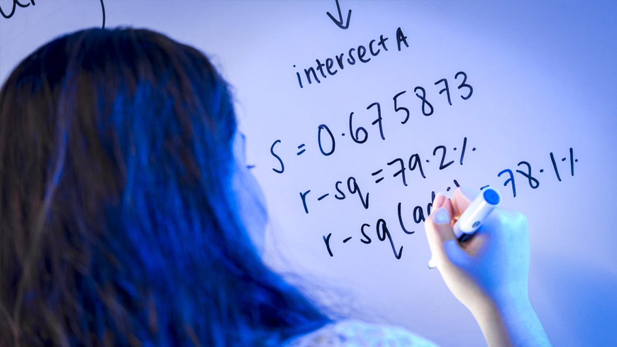 A student writes equations on a whiteboard