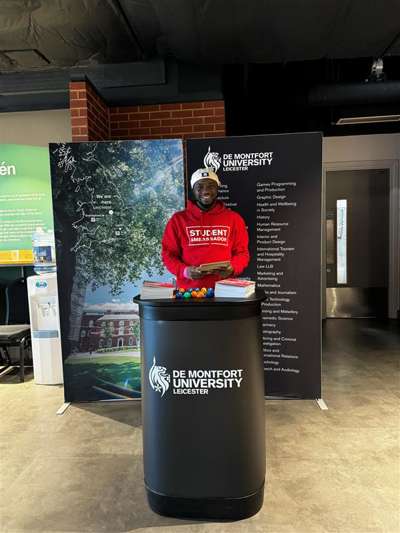 DMU student at an exhibition representing the university and talking about DMU courses to prospective